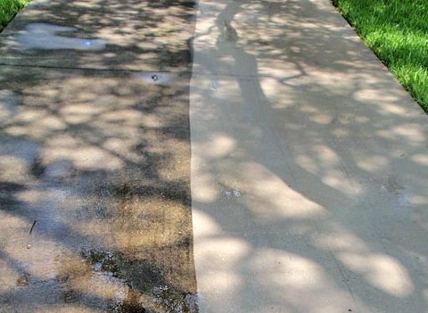 Concrete sidewalk with one half cleaned and the other half still dirty, showing a clear difference in color.